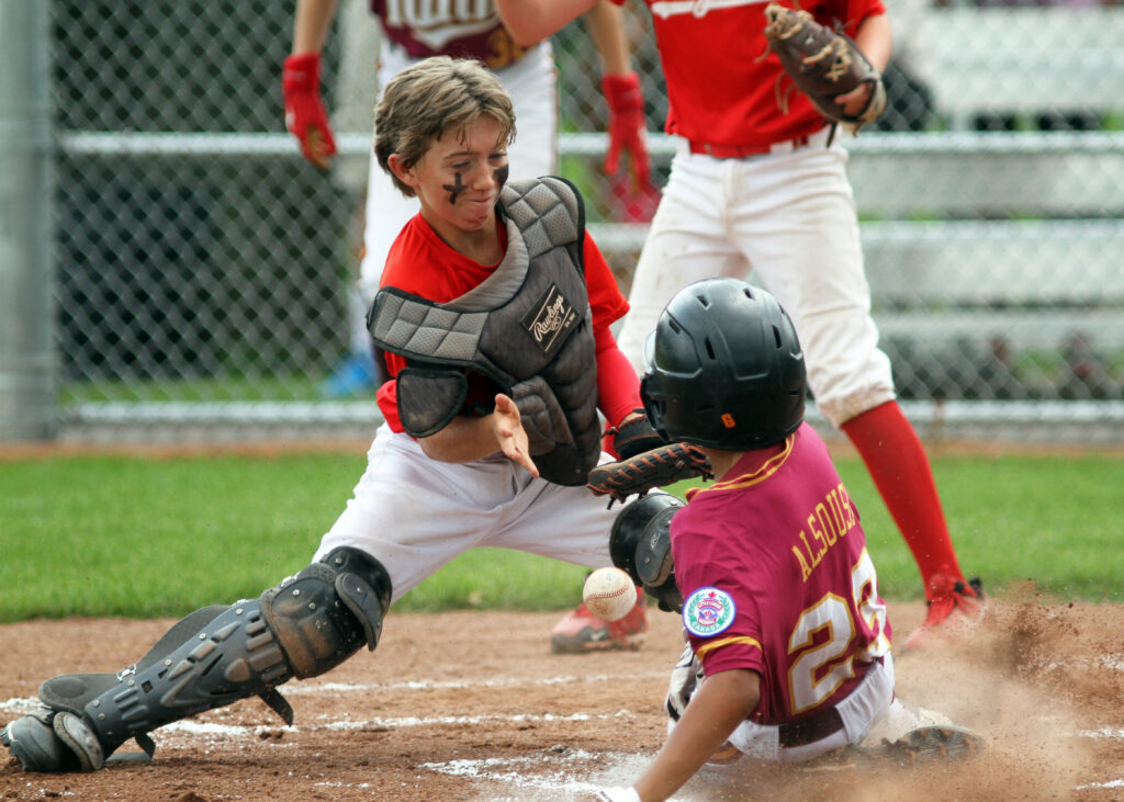 A kid sliding into home base at the Canadian Little League Championships