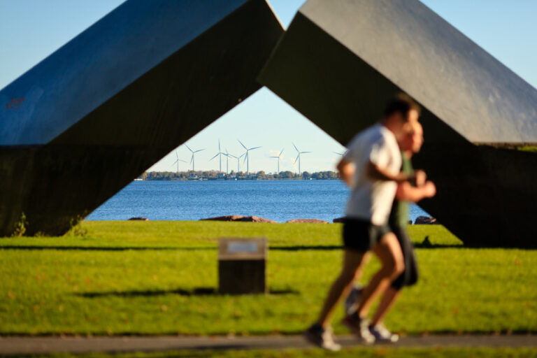 Runners pass by the great time sculpture, which frames the windmills of wolf island