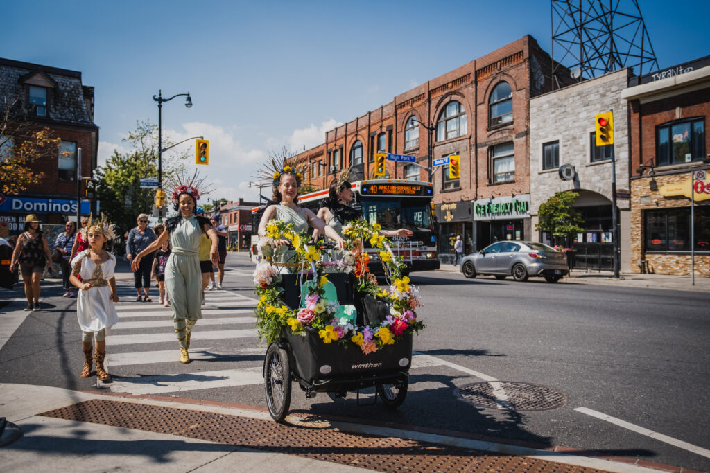 People decorated with flowers walking down the street.