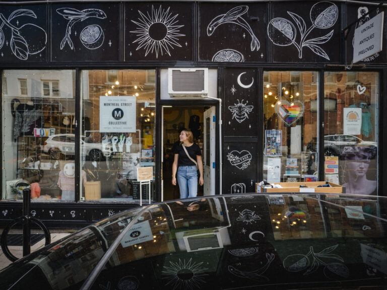 a happy shopper stands in the doorway of montreal thrift admiring the unique black and white painted storefront walls