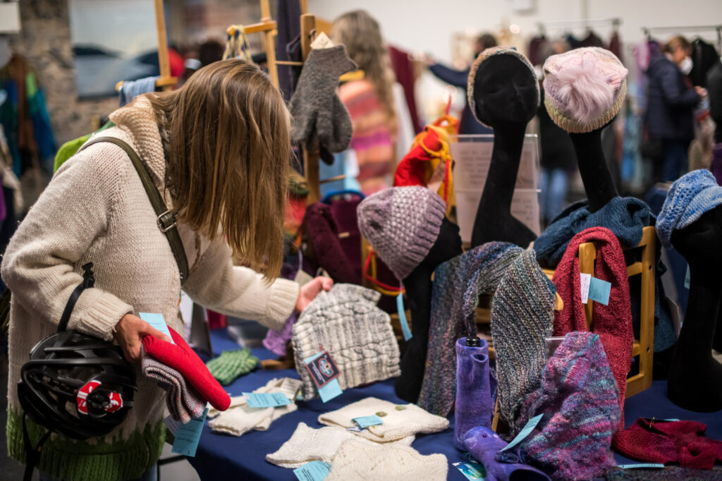 A women looks at hand-knit items at a holiday market. 