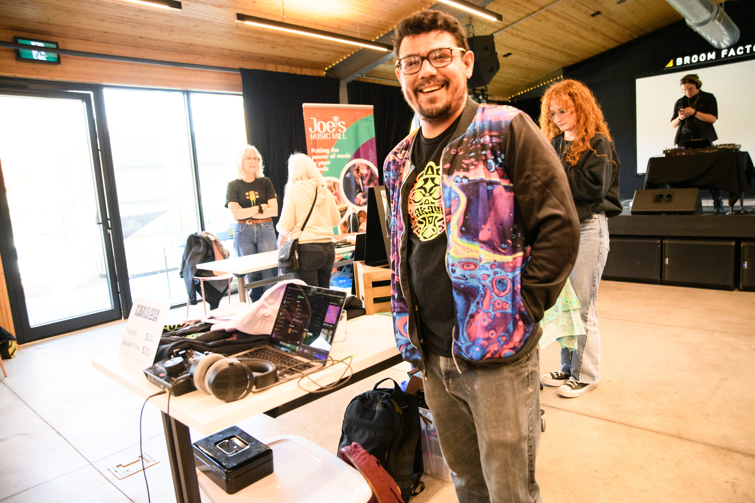 A person smiling at their music merch market vendor table